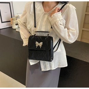Détail du sac à dos plissé noir avec boucle papillon argentée et fines bretelles élégantes