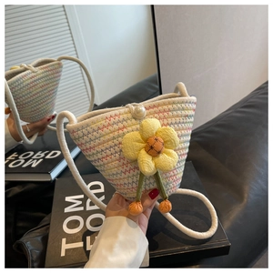 Detail of woven straw bucket bag with sunflower charm and pearl button closure
