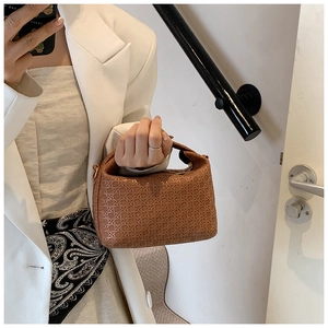 Close-up of brown woven texture and cross-stitch craftsmanship on luxury handbag