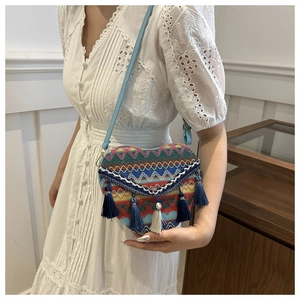 Detailed view of a heart-shaped woven crossbody bag with colorful tassels and thin strap