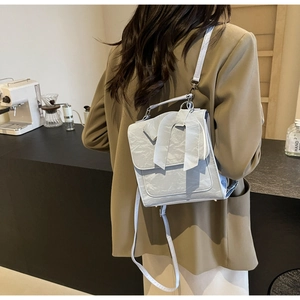 Detail of light blue bow backpack with pleated texture on model in cafe setting