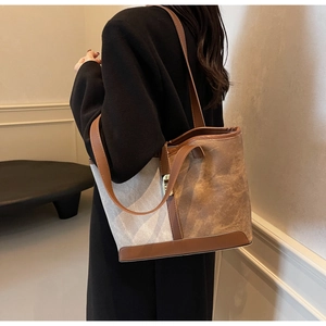 Detail of color-block canvas tote bag with brown leather trim and metal buckles