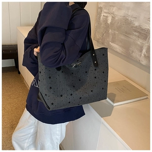 Detail of grey star-print tote bag with silver metal bow and black leather strap