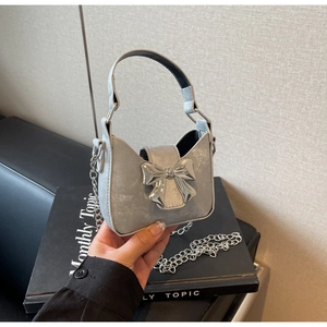 Close-up of a mini silver metallic bag with a bow detail and a chain shoulder strap