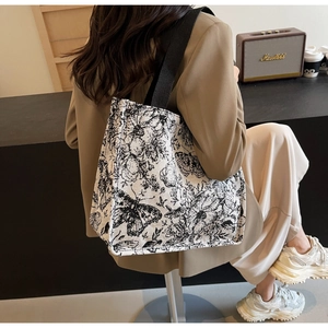 Lifestyle shot showing a large knit tote bag with butterfly print and black strap
