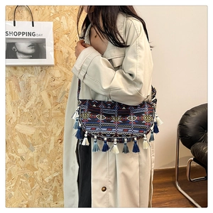 Close-up of Bohemian crescent bag with ethnic patterns and colorful tassels on a model