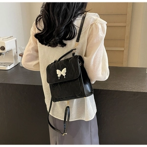 Détail d'un petit sac à dos noir avec nœud blanc et texture en similicuir plissé