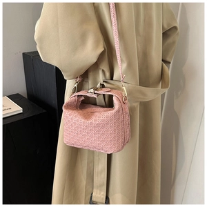 Close-up detail of pink woven handbag with gold metal clasp and textured pattern