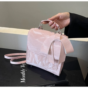 Detailed view of pink crinkled patent leather handbag with a large decorative bow