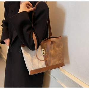 Detail view of contrast color tote bag with leather trim and gold twist lock closure