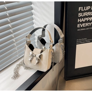 Detailed close-up of a mini bow handbag featuring silver metallic buckle and fine chain strap