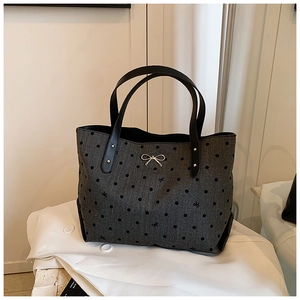 Detail of dark grey polka dot tote bag with metallic silver bow and sturdy black handles
