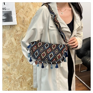 Detailed embroidery and fringe tassels on a bohemian crossbody bag worn by a model