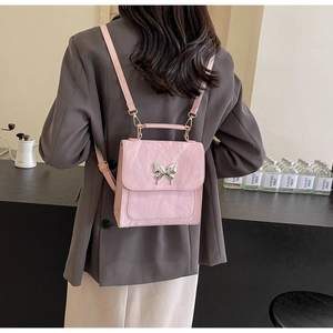 Détail du sac à dos rose avec boucle papillon argentée porté par un mannequin en intérieur