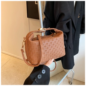 Macro detail of brown woven textured crossbody bag with gold-tone metal hardware