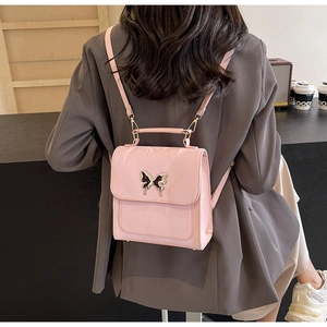 Détail d'un sac à dos rose en cuir avec boucle papillon porté par un mannequin