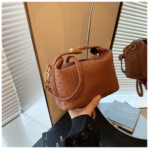 Close-up of caramel woven leather handbag with gold metal clasp and cross pattern detail