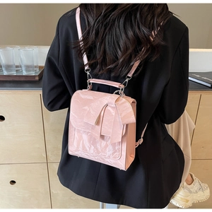 Detail of pink bow shoulder bag with glossy crinkled texture on black blazer