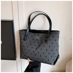 Close-up of gray polka dot tote bag featuring black bow embroidery and silver metal hardware