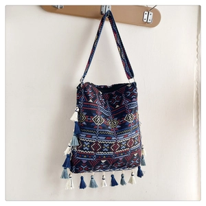 Detail of bohemian tote bag featuring blue geometric patterns and vibrant tassel fringe