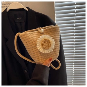 Detail of hand-woven beige bucket bag featuring a white daisy and pearl buckle closure
