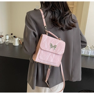 Détail du sac en cuir plissé rose avec fermoir papillon argenté et bandoulière
