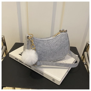 Detail of grey felt crescent bag with V-shaped stitching and white fur ball pendant