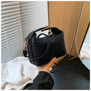 Detail of black woven texture handbag with golden hardware and detachable strap