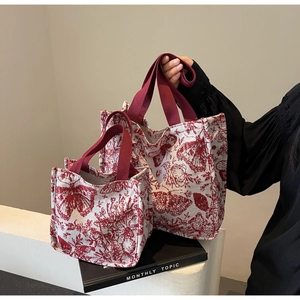 Detailed close-up of red Toile de Jouy floral print on premium white canvas tote bags