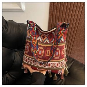 Close-up of woven bohemian tote bag featuring colorful geometric patterns and red tassels