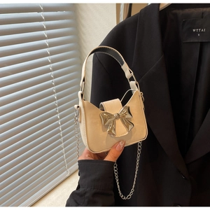 Detailed close-up of a mini bow handbag in cream white with silver chain strap and metal bow