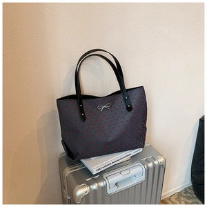 Detailed view of large tote bag with red heart dots and silver bow decoration