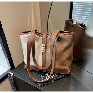 Detail of color-block canvas tote bag featuring premium leather straps and metal twist lock