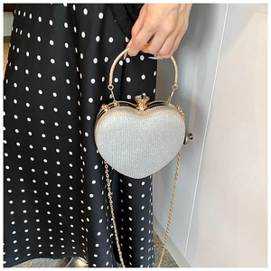 Detail of silver heart-shaped evening bag with gold ring handle and sequin finish