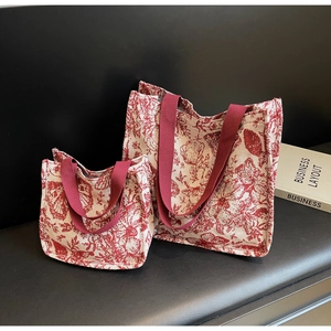 Detail view of two vintage floral canvas tote bags in small and large sizes on a black bench