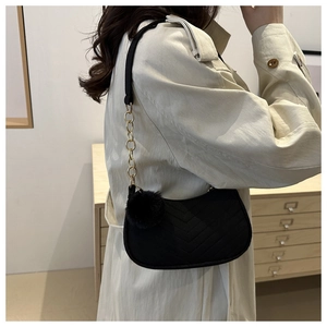 Detail of black V-quilted hobo bag with gold chain strap and plush ball charm