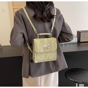 Détail du sac à dos en cuir vert herbe avec textures plissées et fermoir papillon argenté