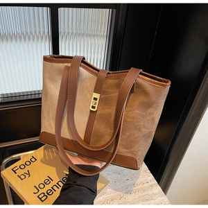 Detail of canvas and brown leather tote bag with a golden metal twist lock closure