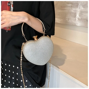 Detail of silver glitter heart clutch bag with gold handle and jewel clasp closure