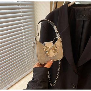 Detail of a shiny silver mini bow handbag with sleek metal chain and top handle