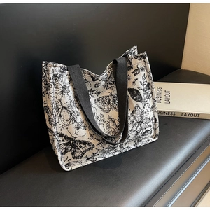Detail of vintage canvas tote bag with black and white floral butterfly print on bench