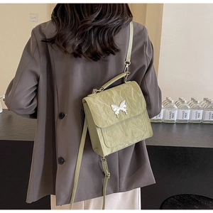 Détail du sac en cuir plissé vert clair avec boucle papillon argentée et bandoulière