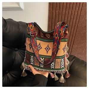 Detail of bohemian tote bag with colorful woven patterns and vibrant pink fringe tassels
