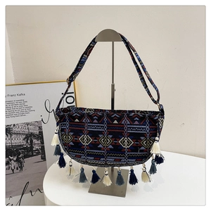Close-up of bohemian shoulder bag with colorful geometric embroidery and fringe tassels