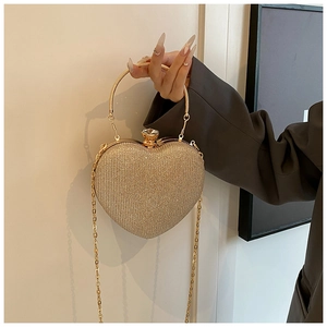 Detail of heart-shaped gold evening clutch with glitter texture and round metal handle