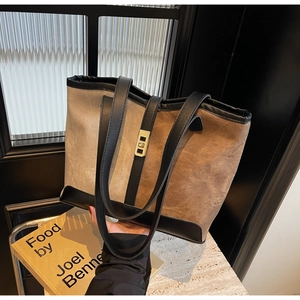 Close-up of contrast color tote bag with golden twist lock and leather handle detail