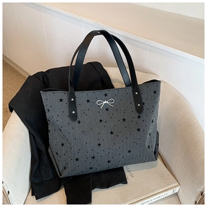 Close-up of grey star pattern tote bag with silver bow charm on a stylish chair