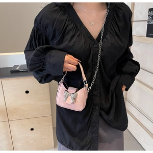 Detailed view of mini pink handbag with silver bow detail and metal chain strap