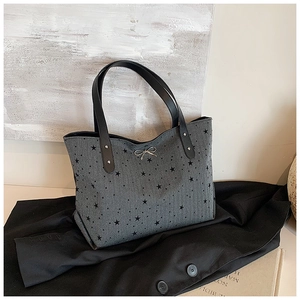 Close-up of grey star print tote bag with silver bow detail on a black blazer