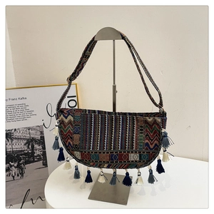 Close-up of bohemian half-moon bag featuring colorful geometric patterns and long tassels